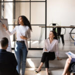 group of people looking at woman giving presentation in white board