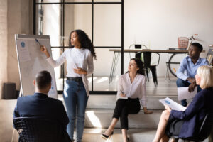 group of people looking at woman giving presentation in white board